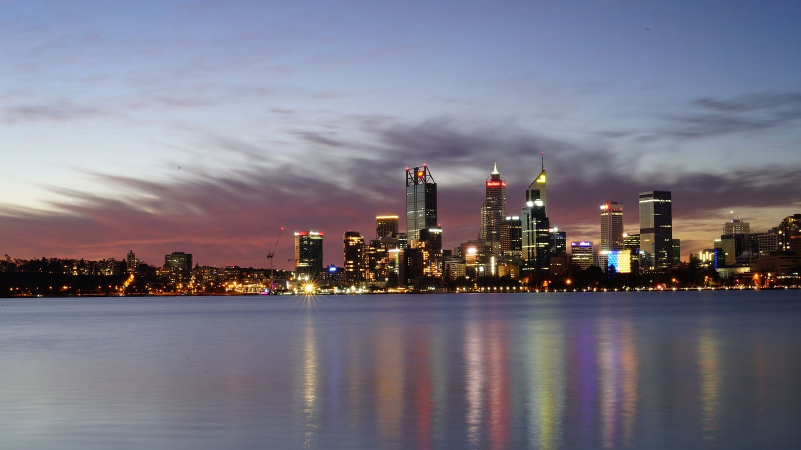 A wide cinematic view of the Perth city skyline during sunset.