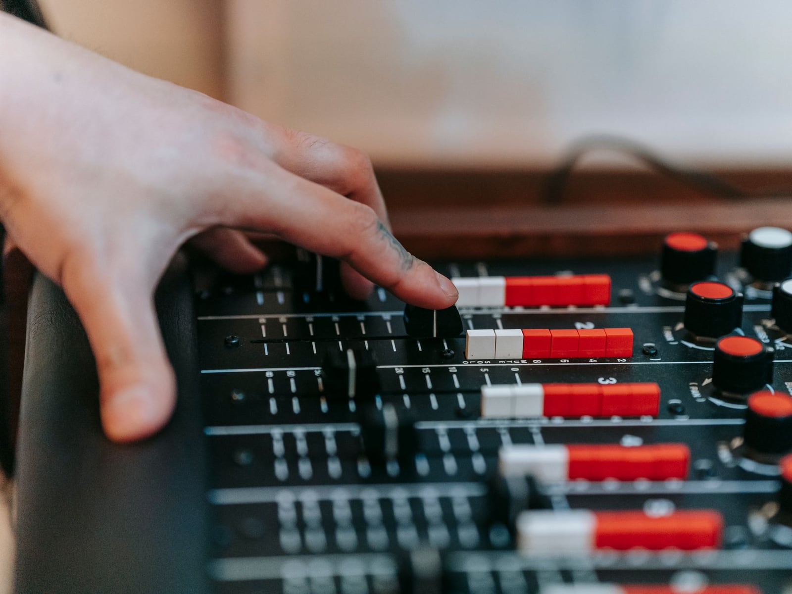 Close-up of a sound engineer adjusting faders on a professional mixing desk during a session.
