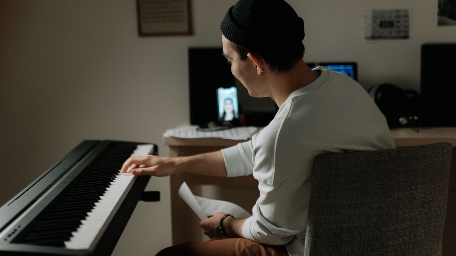 A producer in a home studio collaborating online via a professional microphone and headphones.
